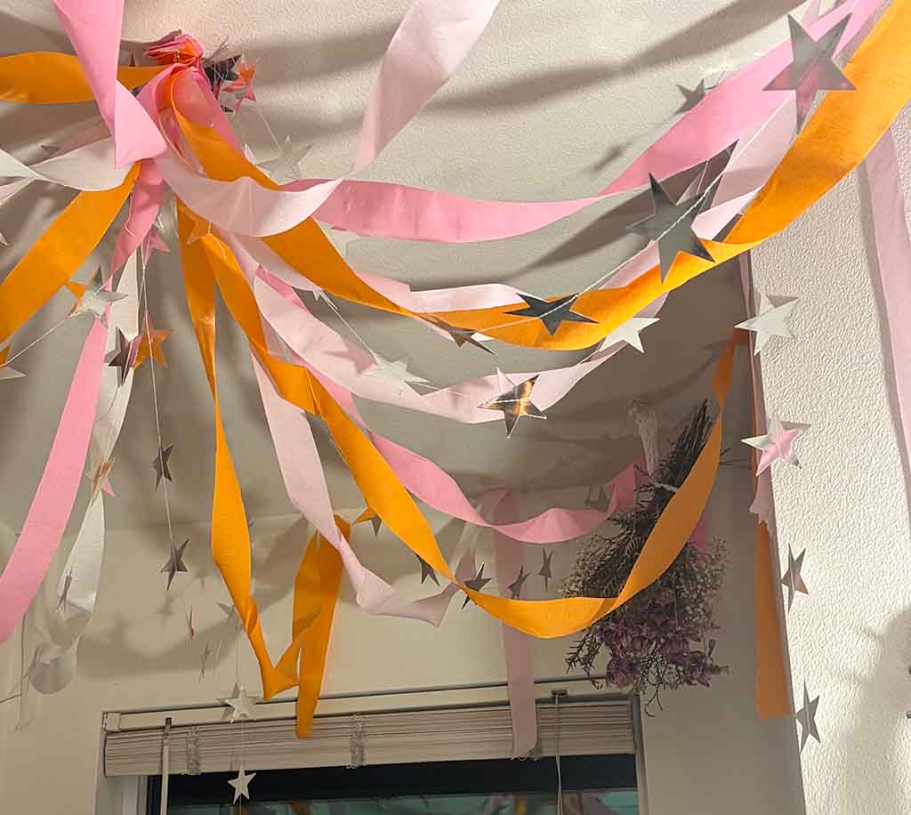 White, pink, and orange streamers are draped from the ceiling with a silver star garland.
