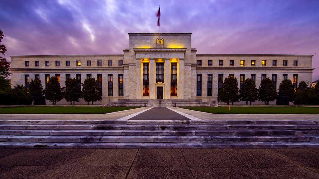 The front of the Federal Reserve building can be seen as the sun sets during the summer in Washington D.C.