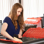 A woman packs a box in her office. Moving for work is made simpler with a job relocation package.