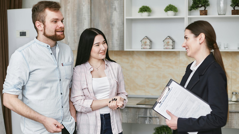 Questions-to-ask-first-time-buyer-1 A young couple is meeting with their real estate agent to ask questions about buying a house.
