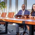 A man and a woman sit in a conference room holding tablets. Are relocation incentives worth it?