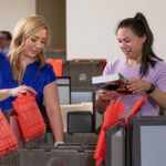 Two women are packing U-Haul Ready-To-Go Boxes® in an office. Many new employees who're relocating for work ask themselves, “How does a relocation package work for new hires?”