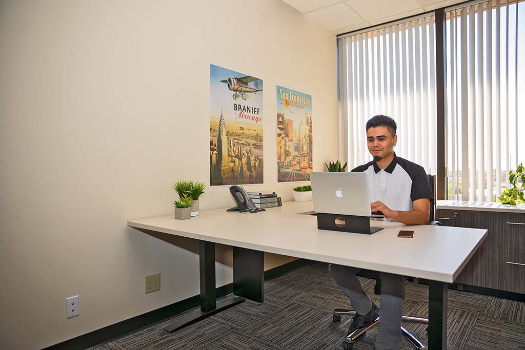A man sits in his office typing on his laptop. Understanding how relocation packages work is important when moving for work.