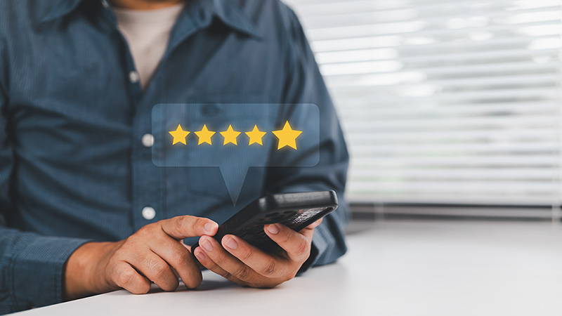 A man looks down at his phone to leave a Moving Help review.