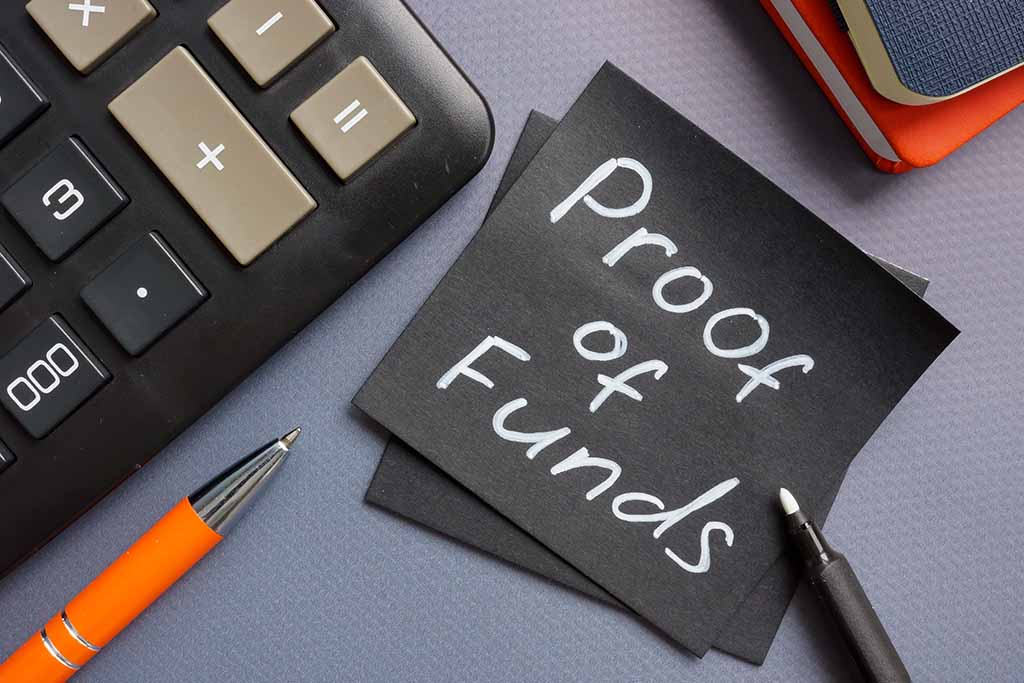 A sticky note has the words “Proof of Funds” written on it. Two pens, two small notebooks, and a calculator surround the two sticky notes.