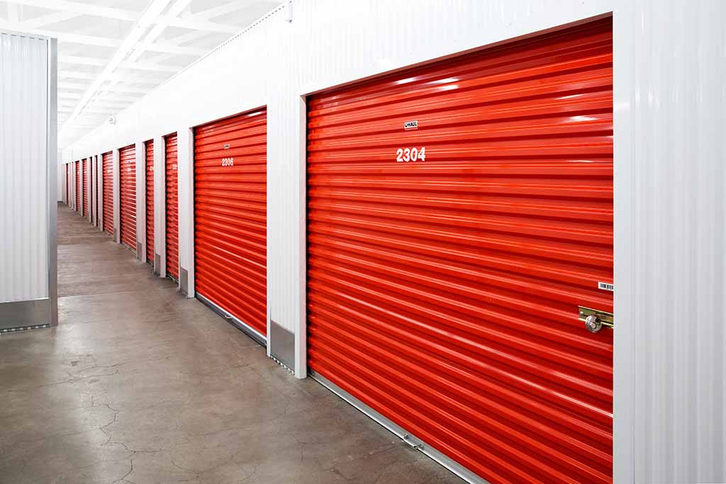 Indoor U-Haul storage units line up next to one another in a well-lit hallway.