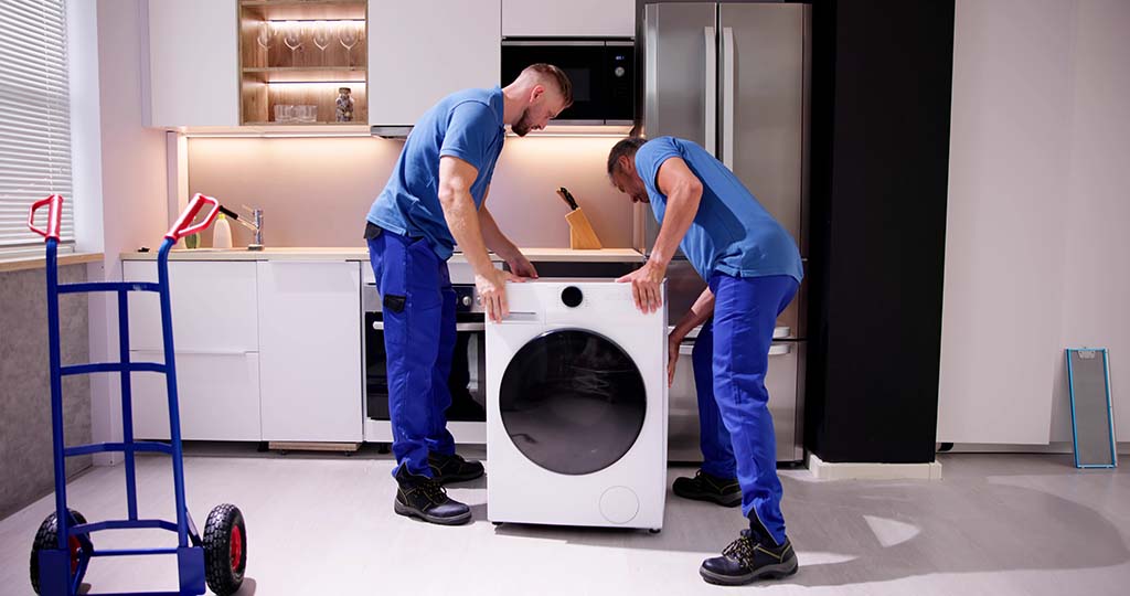 Two movers prepare to move a dryer out of a customer’s home.